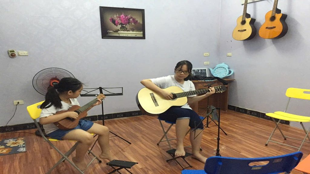Học viên luyện guitar classic Hai học viên luyện guitar classic dây nylon trong lớp học