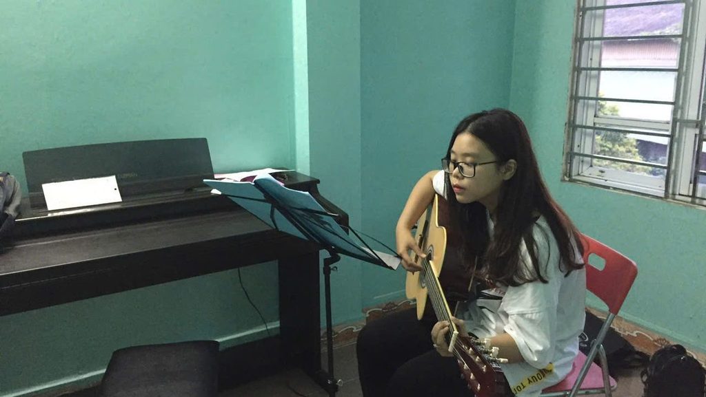 Luyện guitar acoustic với giá nhạc Học viên nữ luyện guitar acoustic cùng giá nhạc