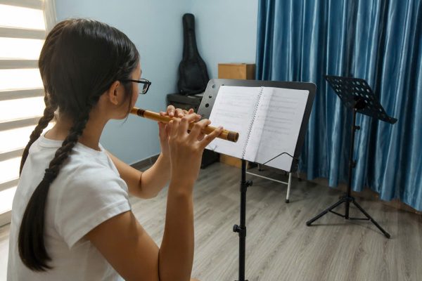 Bé gái đang luyện sáo trúc cùng giáo trình cảm âm tại Sky Music