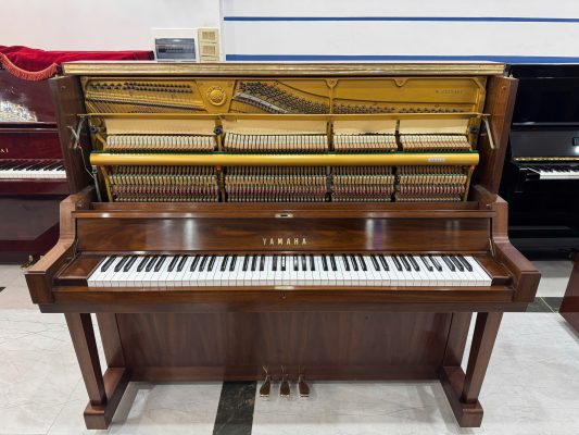 Kỹ thuật viên mở đàn Yamaha W102 để kiểm tra dây đàn và khung nhằm đánh giá độ ổn định cơ học trước khi bán