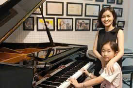 khách hàng trải nghiệm đàn piano cơ tại showroom trước khi mua