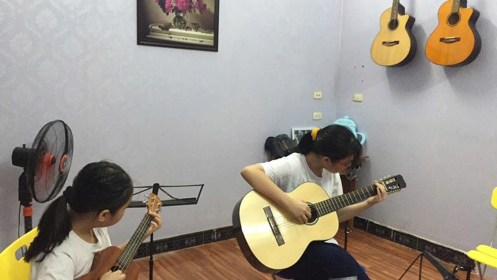 Hai học viên thực hành guitar cùng nhau